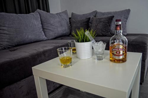 a bottle of alcohol on a white coffee table with a drink at Apartments Good Night in Niš