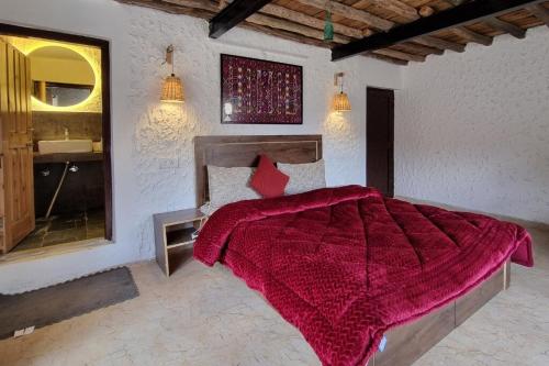 a bedroom with a bed with a red blanket at Spiti Sojourn - Homestay at the Edge in Kaza