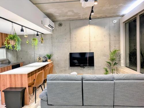 a living room with a couch and a kitchen at 熱海デサイナーズヴィラitsumo in Atami