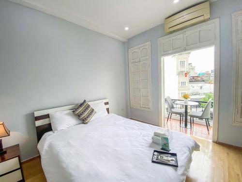 a bedroom with a white bed with a table and a window at Eco Nest Hotel Đình Ngang in Hanoi