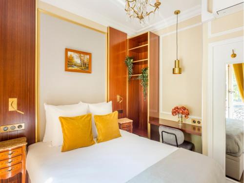 une chambre avec un lit blanc avec des oreillers jaunes dans l'établissement Merveil - Luxury Suite - Marais - Antoine I, à Paris