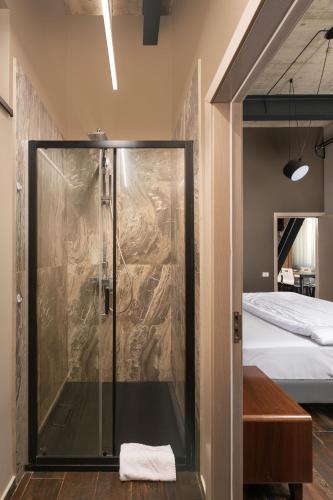 a glass shower in a room with a bed at ArtHomes Apartments in Timişoara