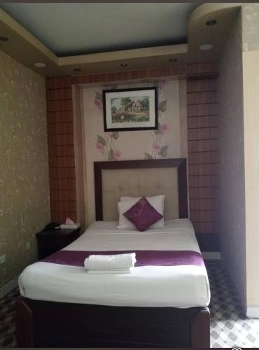 a bedroom with a large bed with purple pillows at Grand Plaza Hotel in Ābdullāpur