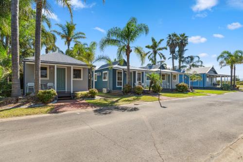 a row of blue homes with palm trees at Batemans Bay Marina Resort in Batemans Bay