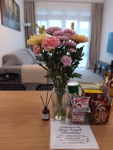 a vase of flowers sitting on a table with a card at Mslim Friendly Stay at Bayu Aisyah Putrajaya, Presint 11 in Putrajaya