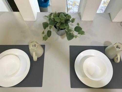 two white plates on a table with a plant at Urban Nest EVO Mall I SOHO I Netflix I WiFi in Bandar Baru Bangi