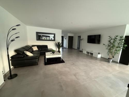 un salon avec un canapé noir et une télévision dans l'établissement Villa Chipie neuve & grand standing !, à Valmont
