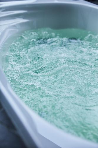 a bath tub filled with green water with bubbles at 宮島離れの宿 IBUKU -Miyajima Hanare no Yado IBUKU- in Miyajima