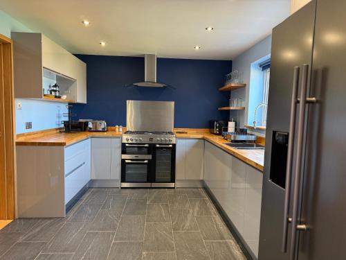 a large kitchen with blue walls and white cabinets at The Sidings, Wool in Wareham