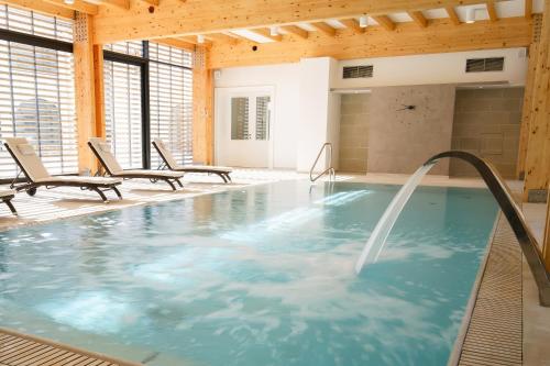 a indoor pool with a hot tub with two chairs at Hotel Château Gbeľany in Žilina