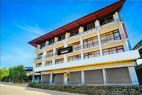 a white building with a red roof at Super Townhouse Madikeri Fort Formerly Hotel Raj in Madikeri