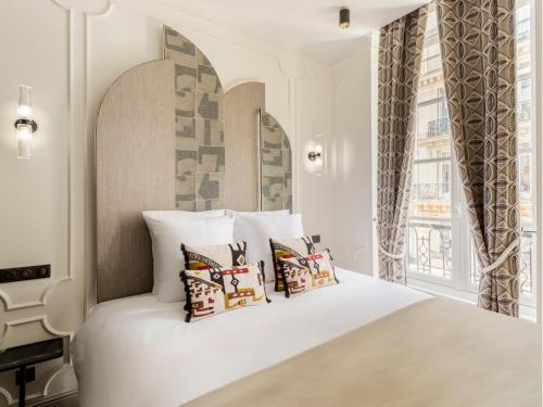 - une chambre avec un lit blanc et des oreillers dans l'établissement Merveil - Signature Suite - Marais - Montmartre, à Paris