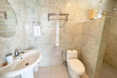 a bathroom with a white toilet and a sink at La Puerta Al Paraizo Guimaras powered by Cocotel in Guimaras