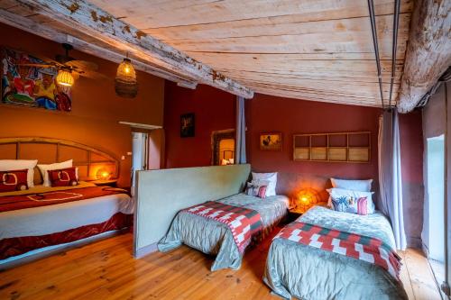two beds in a room with red walls and wooden floors at Prieuré Saint-Louis Maison d'Hôtes in Floure