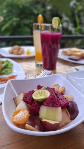 a white plate of fruit on a table with drinks at Asna House in Ubud