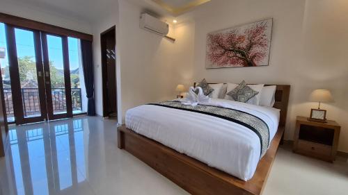 a bedroom with a large bed and a large window at Asna House in Ubud