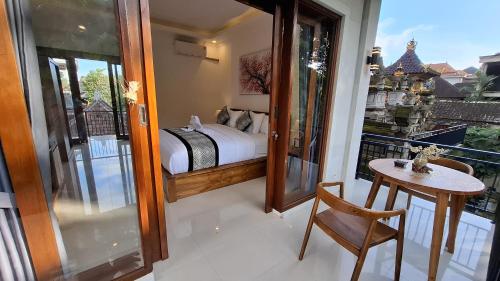a bedroom with a bed and a table on a balcony at Asna House in Ubud