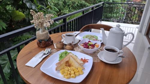 a table with a plate of food and coffee on it at Asna House in Ubud