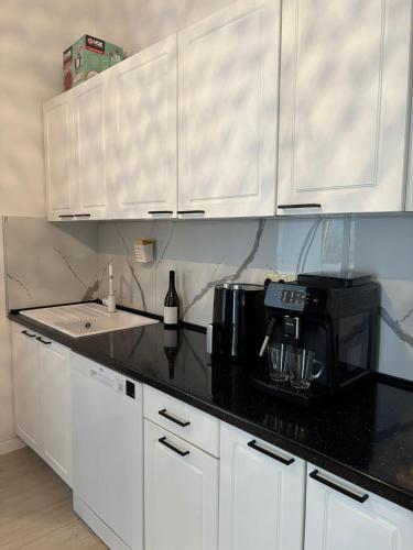 a kitchen with white cabinets and a black counter top at Villa Vita in Mostar