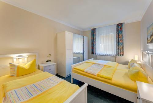 two beds in a small room with yellow sheets at Haus Am Wald in Ahlbeck