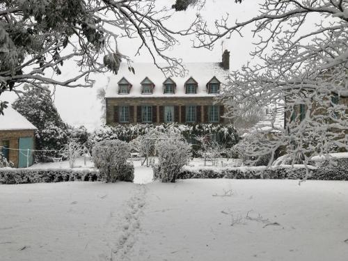 a yard covered in snow with a house in the background at Chambres d'Hôtes Belle Vallee in Domfront