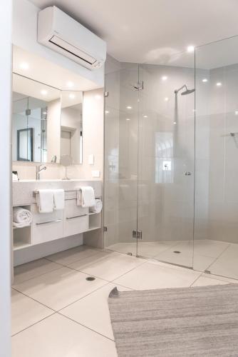 a bathroom with a glass shower and a sink at On The Beach Noosa Resort in Noosa Heads