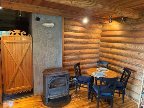a dining room with a table and a wood stove at Atostogų namelis ant ežero kranto in Juočionys