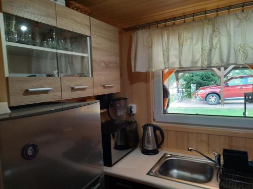 a kitchen with a refrigerator and a sink and a window at Domek letniskowy in Jabłonka