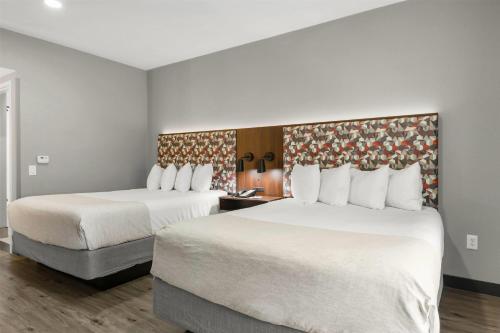 a hotel room with two beds and a chair at Hawthorn Extended Stay by Wyndham College Station in College Station