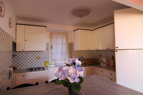 kuchnia z wazą fioletowych kwiatów na stole w obiekcie Five Lands Pink Cottage w mieście Levanto