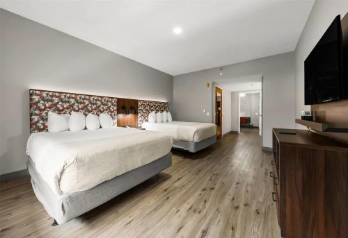 a hotel room with two beds and a flat screen tv at Hawthorn Extended Stay by Wyndham College Station in College Station