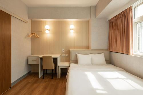 a hotel room with a bed and a desk at Kindness Hotel Weiwuying in Kaohsiung