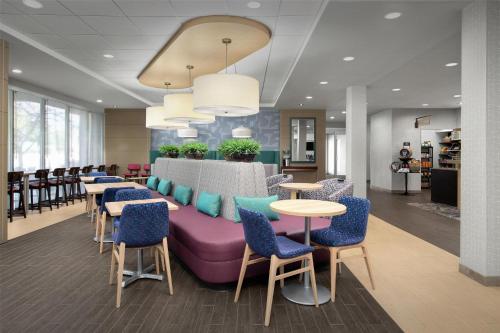 a waiting room with a purple couch and tables and chairs at Home2 Suites Nashville Airport in Nashville