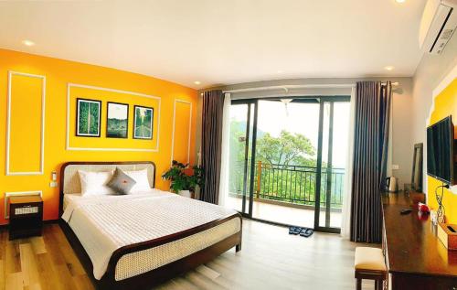 a bedroom with orange walls and a bed and a balcony at Sunset Homestay Villa Tam Đảo in Tam Ðảo