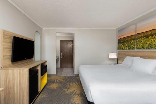 a hotel room with a bed and a flat screen tv at Days Inn & Suites by Wyndham Kansas City - CHIEFS Stadium in Kansas City