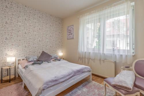a bedroom with a bed and a window and a chair at Király Családi Apartman- Royal Family Apartment #Freegarage in Budapest