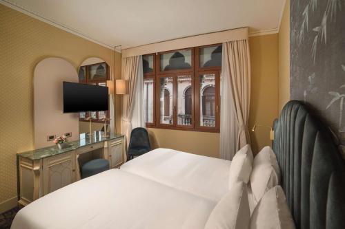a hotel room with a bed and a television at NH Venezia Santa Lucia in Venice