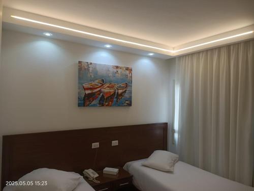 a hotel room with two beds and a painting on the wall at Salma Hotel Cairo in Cairo