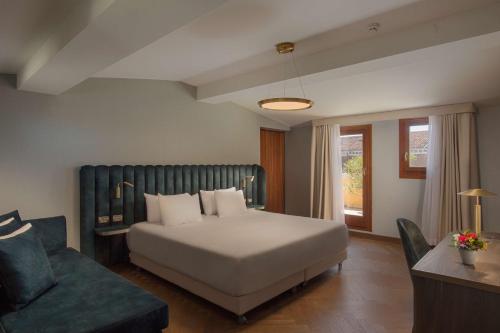 a bedroom with a bed and a couch and a chair at NH Venezia Santa Lucia in Venice