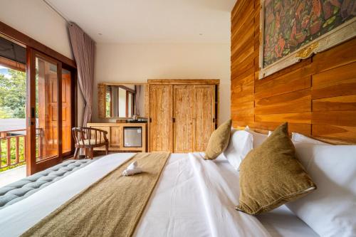 a bedroom with a large white bed with a wooden wall at Angseri Villas in Tabanan