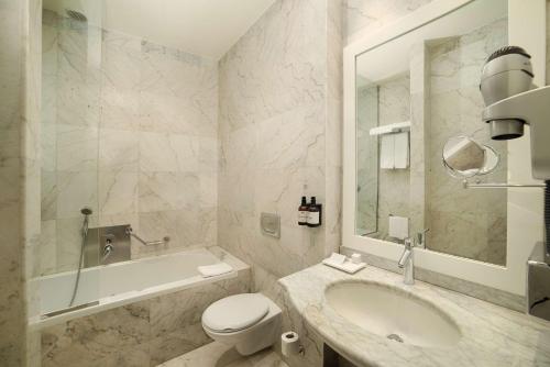 a bathroom with a tub and a toilet and a sink at NH Venezia Santa Lucia in Venice