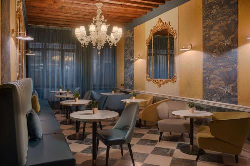 a restaurant with tables and chairs and a chandelier at NH Venezia Santa Lucia in Venice