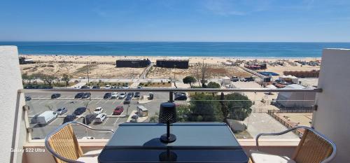 a table on a balcony with a view of the beach at Pé no mar in Monte Gordo