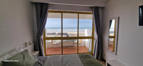 a bedroom with a large window with a view of the ocean at Pé no mar in Monte Gordo