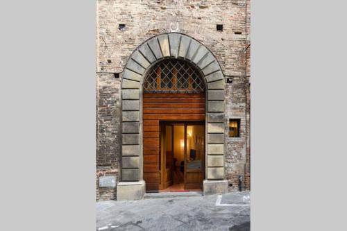 een toegang tot een bakstenen gebouw met een houten deur bij Rinidia - Siena Centro in Siena