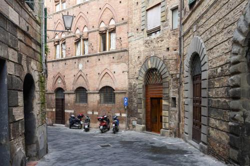 twee motorfietsen geparkeerd in een steegje naast een gebouw bij Rinidia - Siena Centro in Siena