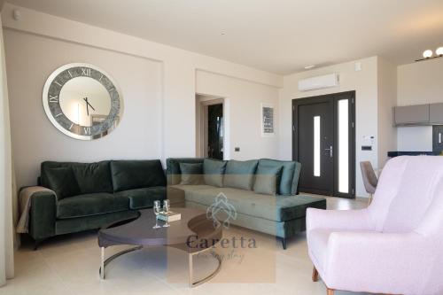 a living room with couches and a clock on the wall at Gem Villas Luxury Sea View in Karavadhos