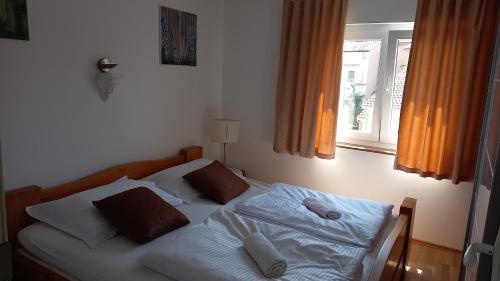 łóżko z białą pościelą i poduszkami w sypialni w obiekcie D,apartman w mieście Omišalj