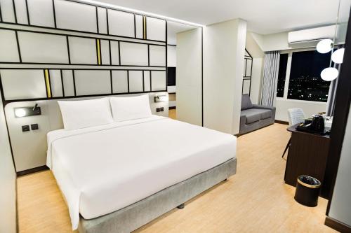 a bedroom with a large white bed and a chair at Yello Hotel Samarinda in Samarinda
