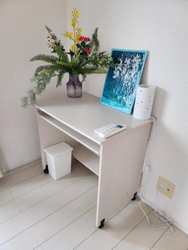a white desk with a vase of flowers on it at 水族館に近いゆったり別荘-Ent Terrace Okinawa in Motobu